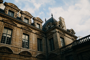 Sticker - Low angle shot of a brown building with large windows under the clouds