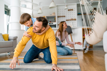 Wall Mural - Happy young family having fun times and playing together at home