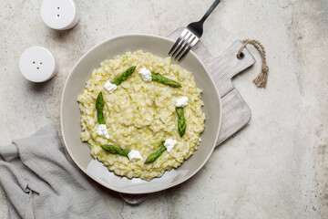 Rice dish - risotto with asparagus and soft cheese. Stone background. Flat lay, copy, space.