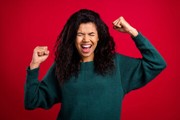 Sticker - Photo of happy nice young dark skin woman raise fists winner good mood smile isolated on red color background