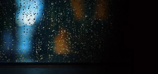 Wall Mural - Rain drop on window at night. Condominium or apartment living room window on rainy season night in Bangkok Thailand. Outside window is blurred bokeh of raining city light and natural tree and sky. 