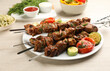 Metal skewers with delicious meat and vegetables served on white wooden table