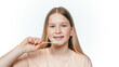 Smiling blonde girl with orthodontic braces holding holding an eco friendly bamboo toothbrush