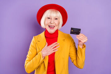 Canvas Print - Portait of impressed short hairdo senior lady show card wear yellow jacket cap isolated on purple background