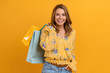 beautiful attractive smiling woman in yellow shirt and jeans holding shopping bags