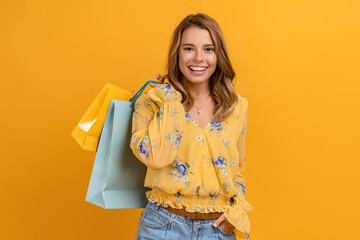 Wall Mural - beautiful attractive smiling woman in yellow shirt and jeans holding shopping bags