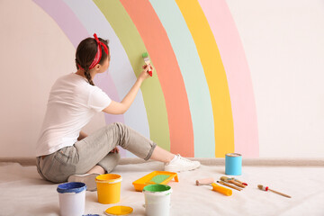 Wall Mural - Young woman painting rainbow on white wall indoors