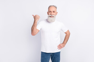 Sticker - Photo of cheerful grey hair beard old man point empty space wear white t-shirt jeans isolated on grey color background