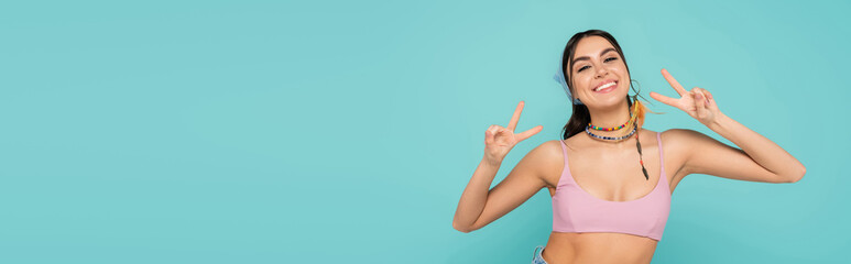 Sticker - Smiling woman in top showing victory gesture isolated on blue, banner.