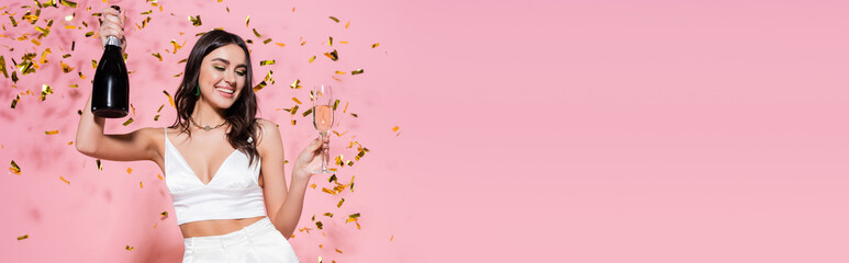 Canvas Print - Stylish woman with champagne near festive confetti on pink background, banner.