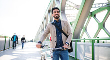Young Business Man Commuter With Bicycle Going To Work Outdoors In City, Walking On Bridge.