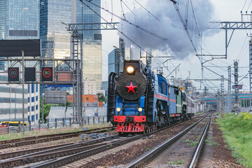 Wall Mural - Retro steam train on Moscow city background.