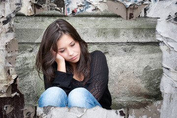 Torn photo of a sad teenage girl looking thoughtful about troubles pinned on an old wooden wall with paper leftovers