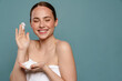 © Drobot Dean - Ginger woman wearing towel smiling while showing cosmetic foam