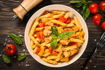 Canvas Print - Pasta with chicken and vegetables at wooden table. Traditional italian food. Top view.