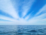 Fototapeta Tęcza - white wispy cirrus cloud burst pattern in blue sky over calm Lake Michigan water