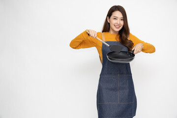 Young Asian woman housewife wearing kitchen apron cooking and holding pan and spatula isolated on white background