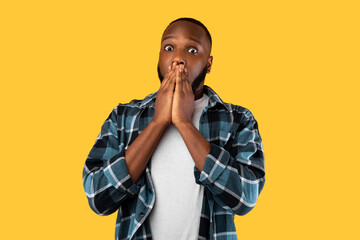 Wall Mural - Shocked Black Millennial Male Covering Mouth Posing On Yellow Background