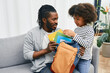 © Peakstock - Father helps daughter to put color copybooks in school bag before a school day
