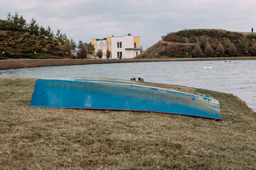 the blue boat lies overturned on the shore of the lake among the hills