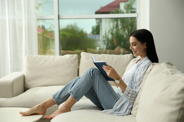 Poster - Young woman reading book on sofa at home, space for text