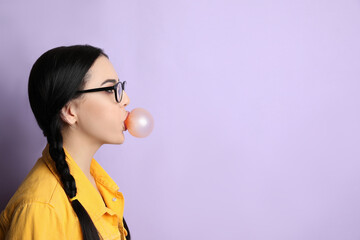 Wall Mural - Fashionable young woman with braids blowing bubblegum on lilac background, space for text