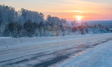 Winter, Frosty Morning Landscape Of The Rising Sun With Sun Glare On The Background Of A Slippery, Icy Highway, Road, Mountainside And Northern Forest Of The Cold Arctic Zone