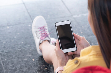 Fototapete - Closeup view of woman hand holding black screen smartphone while sitting outdoors with copy space.