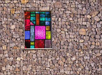 Stained glass in the wall of the house with decorative stone trim reinforced with metal mesh