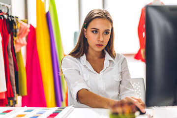 Wall Mural - Portrait of young beauty pretty woman fashion designer stylish sitting and working.Attractive young girl use desktop conputer and colorful fabrics at fashion design studio