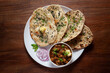Close-up of fresh, hot tandoori roti or butter naan garnished with black till and green fresh coriander leaves and chole. A typical, traditional north indian panjabi food.