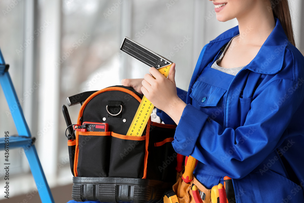 Beautiful female electrician with tools in room, closeup
