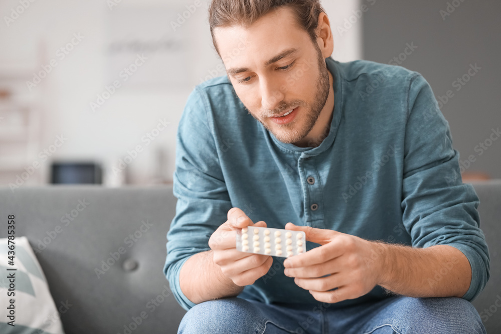 Handsome young man with pills at home