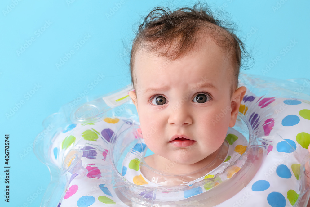 Cute baby with inflatable ring on color background, closeup