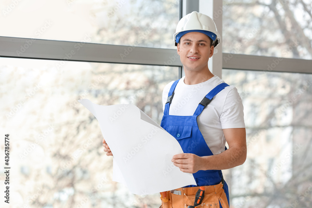 Young electrician with house plan in room