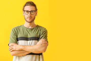 Canvas Print - Young man wearing eyeglasses on color background