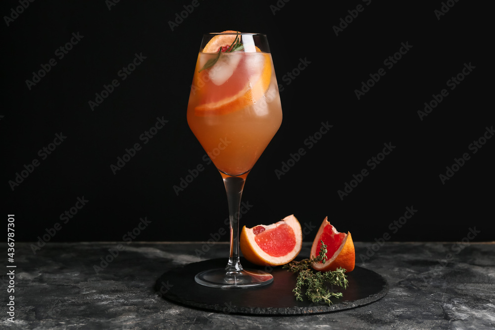 Glass of tasty grapefruit cocktail on dark background