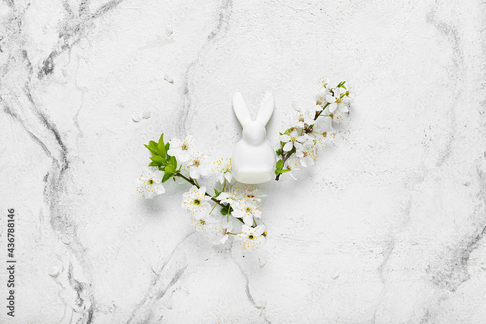 Beautiful blooming branches and bunny figure on light background