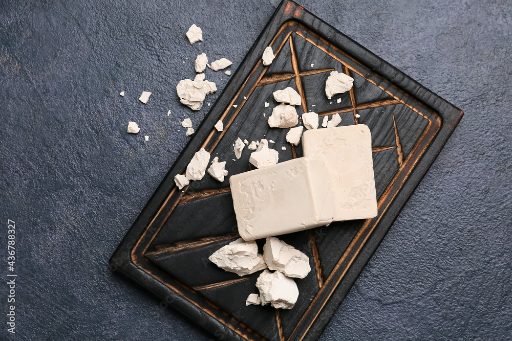 Board with fresh yeast on dark background
