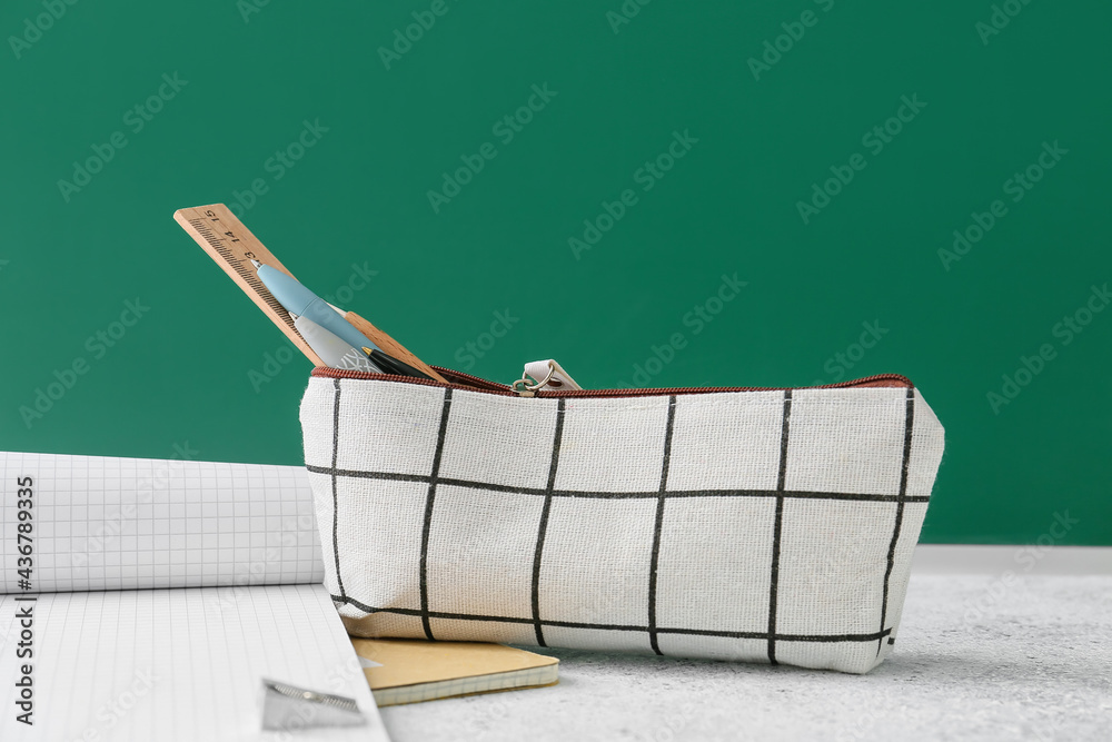 Pencil case and stationery on color background