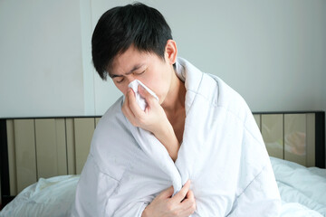 Sick man is flu, using a paper napkin and he have a runny nose. And he was covered in warm cloth.Health concept