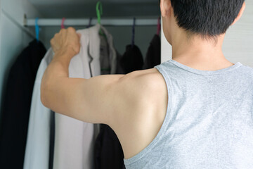 young man standing select  a shirt and a suit to work in. At the wardrobe in his house.