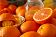 A closeup view of a display of oranges and the process of making a glass of orange juice.