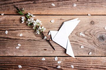 Wall Mural - Paper origami dove of peace with apple blossom branch on old wooden background.