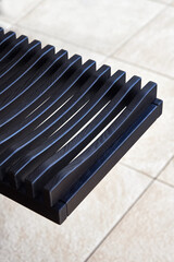 Wall Mural - Stylish dishes drying rack made of toned black solid ash in summer kitchen extreme close view