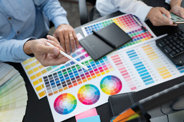 Poster - graphic designer team working on web design using color swatches editing artwork using tablet and a 