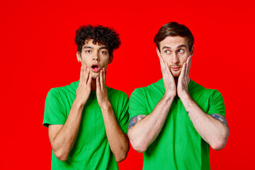 Cheerful friends in green t-shirts hold on to the face of emotion