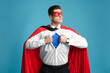 © New Africa - Businessman in superhero cape and mask taking shirt off on light blue background