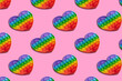 Rainbow heart shape isometric pattern of silicon toy for kids. Pop it fidget toy on pastel background. Simlpe dimple toy on pink pastel background. 