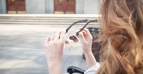 Wall Mural - Young woman holding sunglasses in outdoors.